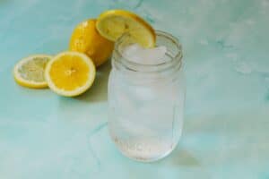 A mason jar with a diy electrolyte drink next to some lemon slices.